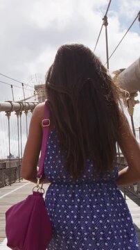 New York City Woman. Young woman on Brooklyn bridge, New York city NYC, Manhattan, USA. Walking young professional in blue dress.