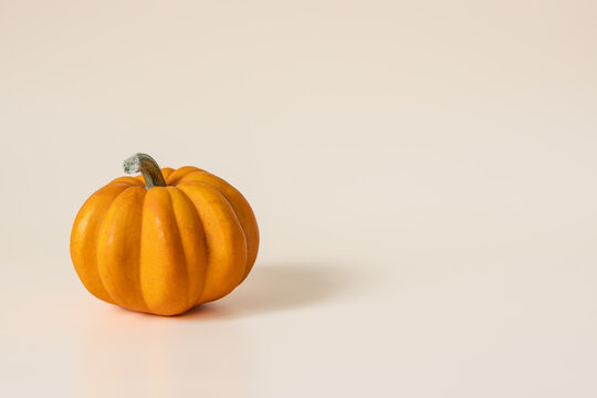 Orange pumpkin on beige background with copy space