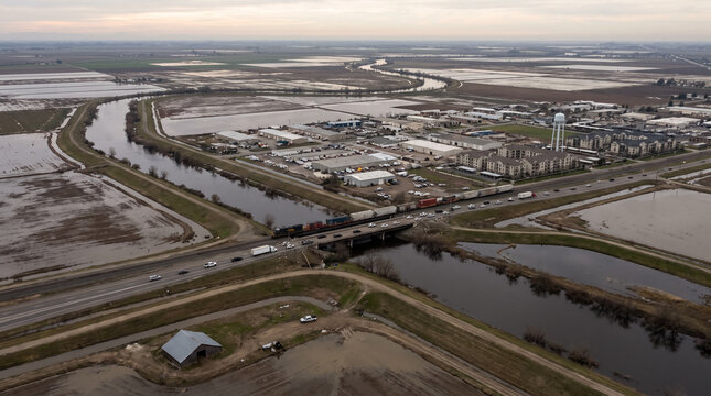 Aerial view of flooded agricultural fields levees canal highway bridge and industrial area. Concept of river, floodplain, wet, drainage canal, freight train.