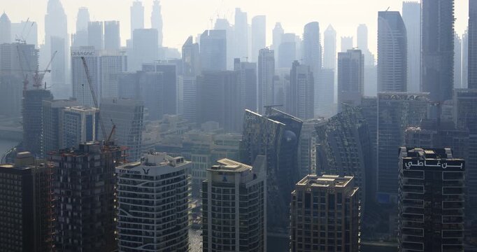 DUBAI, UAE - SEPTEMBER 3, 2026: Dubai Business Bay modern towers and DAMAC buildings stand along the Dubai Water Canal during a hazy daytime, filmed in timelapse