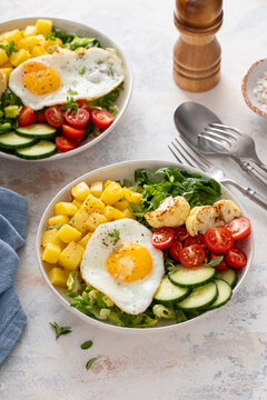 Healthy breakfast or lunch bowl with cooked potatoes, fresh vegetables and fried egg