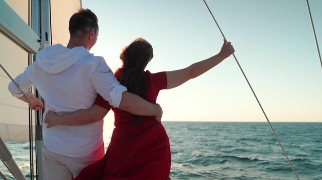 Yacht under sail glides through sea, man woman in love embrace on deck. Sail towards your dreams adventures. Captain Man woman travel on yacht under white sails. Sea voyage with free wind. Romance sea