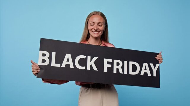 Portrait of smiling Caucasian young adult woman holding Black Friday promotional sign. Clip suitable for seasonal discount campaigns, retail marketing, e-commerce sale announcements