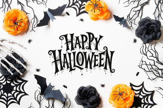 Happy Halloween lettering framed by black and orange roses, spiderwebs, bats and skeleton hands on white, ideal for cards, invitations, posters and seasonal advertising.