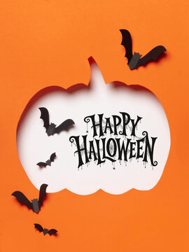 Happy Halloween lettering inside a white pumpkin silhouette with flying black bats on an orange background, ideal for cards, invitations, posters and seasonal advertising.