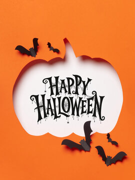 Happy Halloween lettering inside a white pumpkin silhouette with flying black bats on an orange background, ideal for cards, invitations, posters and seasonal advertising.