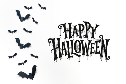 Happy Halloween lettering with a swarm of flying black bats on a white background, ideal for greeting cards, invitations, posters, banners and seasonal advertising.