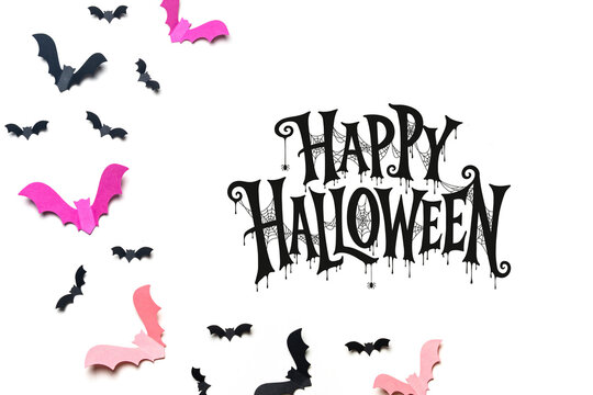 Happy Halloween lettering surrounded by black and pink flying bats on a white background, ideal for greeting cards, party invitations, posters, stickers and seasonal advertising.