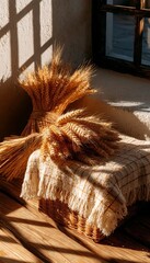 Obraz premium Minimal Harvest Composition Featuring Wheat Bundles And A Textured Beige Throw On A Wooden Surface.