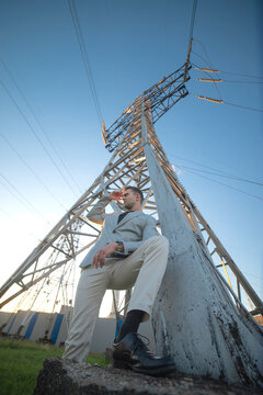 Professional manager supervising power grid standing near high voltage electricity tower with copy space