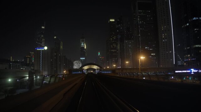 DUBAI, UAE - AUGUST 29, 2026: Dubai Metro travels along elevated tracks through illuminated towers in Dubai UAE, with a KFC billboard appearing beside the railway at night
