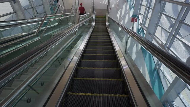 DUBAI, UAE - AUGUST 29, 2026: Escalator descends through a glass walled Dubai Metro station in Dubai UAE, passing a commuter on the adjacent escalator