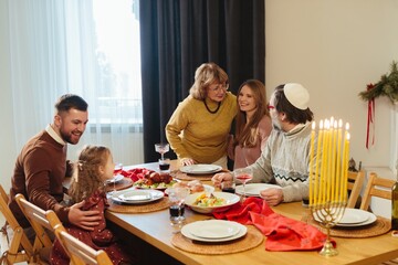 Family celebrating hanukkah with menorah candles lit