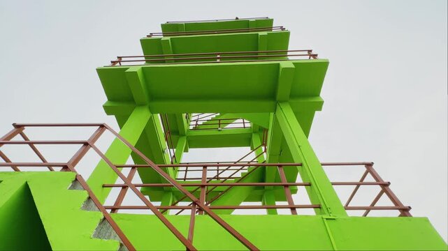 Slow tracking shot of a multi tiered green watchtower structure designed for viewing agricultural land forest areas and natural surroundings