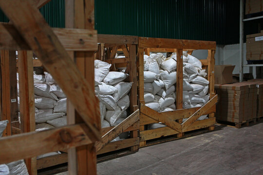 Wooden crates filled with white sacks. Industrial warehouse interior. Green wall background. Storage facility. Logistic supply