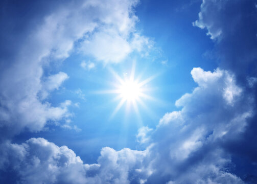 BBright sun shining through dramatic white clouds in a deep blue summer sky, creating a luminous natural weather background with strong sunlight and atmospheric depth.