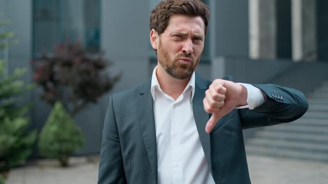 Portrait upset stressed Caucasian middle-aged business man showing thumb down in city sad dissatisfied businessman male demonstrate dislike manager professional specialist with bad result in downtown