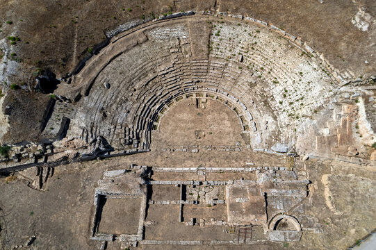 Aerial view of the ancient theater of Sicyon in Corinthia, Greece, showing its semicircular cavea, stepped stone seating, orchestra, stage foundations and surviving architectural remains.