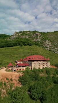Aerial view of historic castle showcasing traditional architecture nestled in a lush green mountain valley