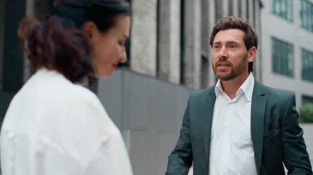 Two stressed business colleagues in city Caucasian businessman angry talking yelling to businesswoman intern worker sad listening in downtown. Leader man talk yell with rage to woman quarrel outdoors