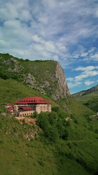 Aerial view of historic castle showcasing traditional architecture nestled in a lush green mountain valley