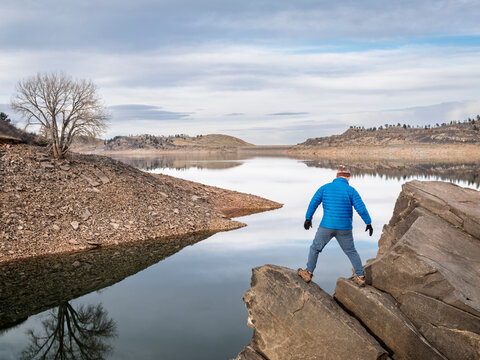 male hiker on a rocky shpre of Horsetooth Reservoir - a popular recreational area in northern Colorado in fall or winter scenery