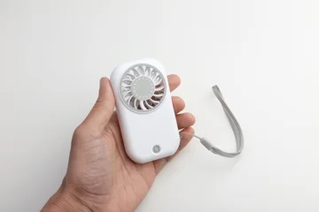 Hand Holding White Portable Mini Fan with Lanyard on White Background © stasknop