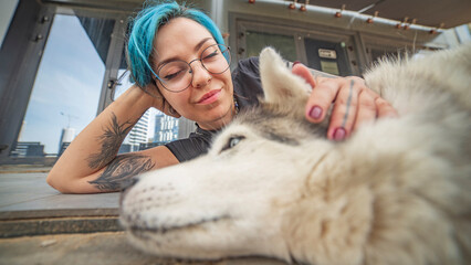  Tender moment of young alternative woman petting her husky dog close up with copy space © Aliaksei