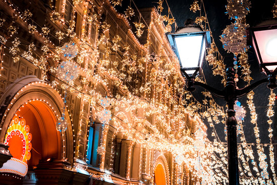 Festive Christmas Lights Draped Over Ornate City Street and Lamp Posts at Night in Winter