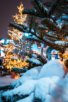 Snowy Christmas Tree With Blue Snowflake Ornament and Warm Bokeh Lights in Winter Night