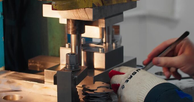 Close-up of industrial manufacturing equipment and machine operator performing routine production