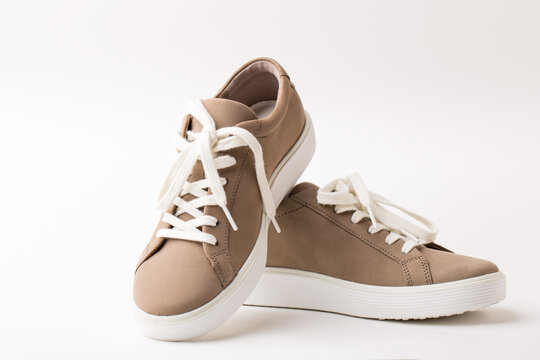 Pair of beige nubuck leather sneakers on white background.
