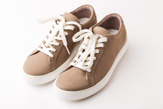 Pair of beige nubuck leather sneakers on white background.