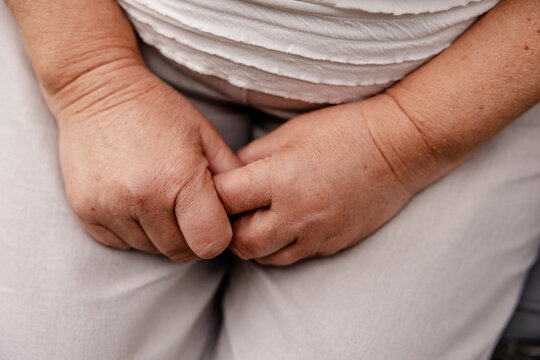 close up of older woman's clasped hands resting in her lap while seated