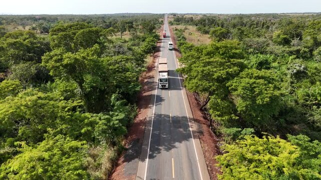 Aerial drone view of busy highway with trucks through Cerrado forest, Mato Grosso, Brazil