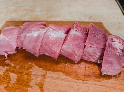 Cut pieces of meat on a wooden board in a kitchen