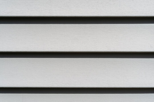 Close view of rows of old green vinyl siding in the sun.