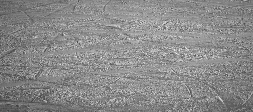 Snowy abstract off-piste skiing background with ski and snowboard trails and tracks on new virgin powder snow. morning sunrise or day time at skiing resort