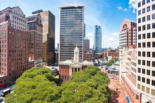Aerial view of the Connecticut Old State House surrounded by historic and modern skyscrapers in downtown Hartford, Connecticut, on a sunny day.