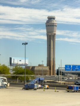 LAS VEGAS, NV, APR 28, 2026: Tall airport control tower rising above ground equipment, a fence, and terminal signage for Terminal 1 and Terminal 3