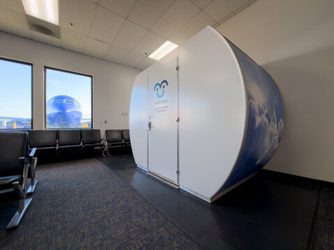 BURBANK, CA, APR 28, 2026: Mamava lactation pod stands in an airport gate area, with black chairs and a Southwest jet visible through the window