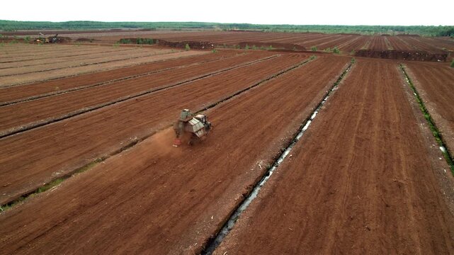 Peat Harvester Tractor on Collecting Extracting Peat. Mining and harvesting peatland. Area drained of mire are used for peat extraction. Drainage and destruction of bogs. Peat harvesting.