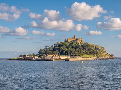 Malerische Ansicht von St Michael&rsquo;s Mount in Cornwall mit mittelalterlicher Burg, gr&uuml;ner Insel und blauem Meer unter einem wolkigen Himmel.
