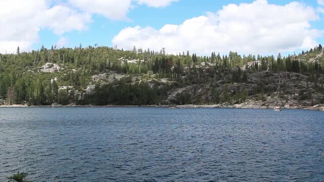 Small Waves On Lake With Tree Covered Mountain Blue Sky White Clouds And Boats In Background Pinecrest California
