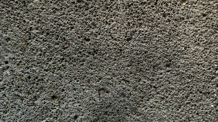 Dark grey porous volcanic basalt rock texture background