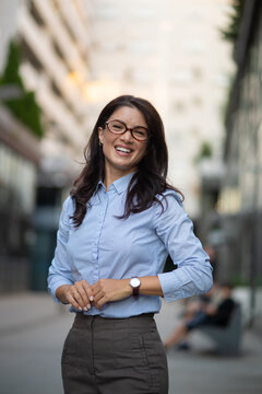 Businesswoman with glasses laughing outdoors in urban setting