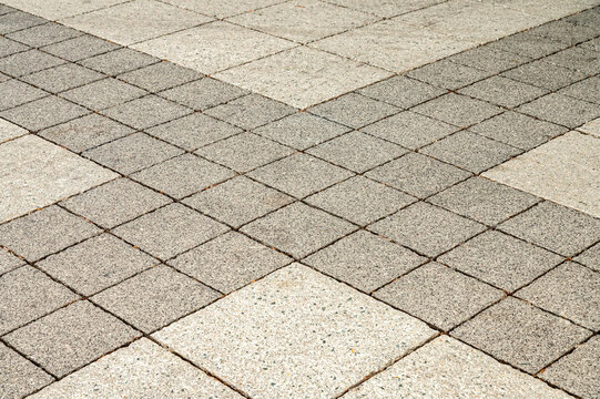 Square concrete paving slabs forming a geometric diagonal cross pattern on city street ground. Perfect for landscaping surface backgrounds, walkway construction and architectural tiles