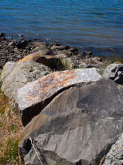 Weathered coastal boulders along a sunny rocky shoreline © mcgimpseymike