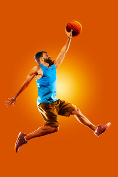Basketball. Professional basketball player on an orange background. Basketball in action. Basketball theme. Sport.