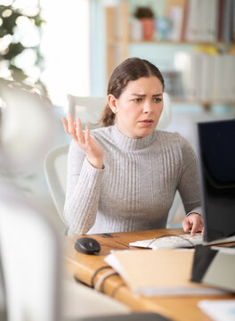 Sad young woman with problems at work working at computer in office